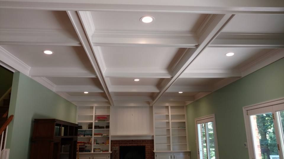 A living room with a coffered ceiling and a fireplace.