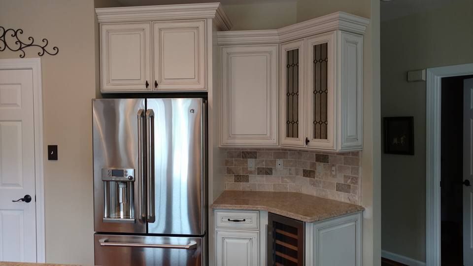 A kitchen with white cabinets and a stainless steel refrigerator.