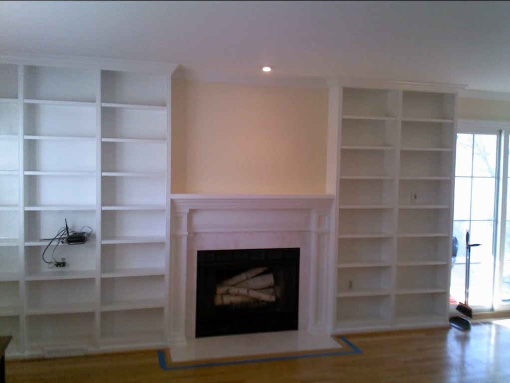 A living room with a fireplace and lots of shelves
