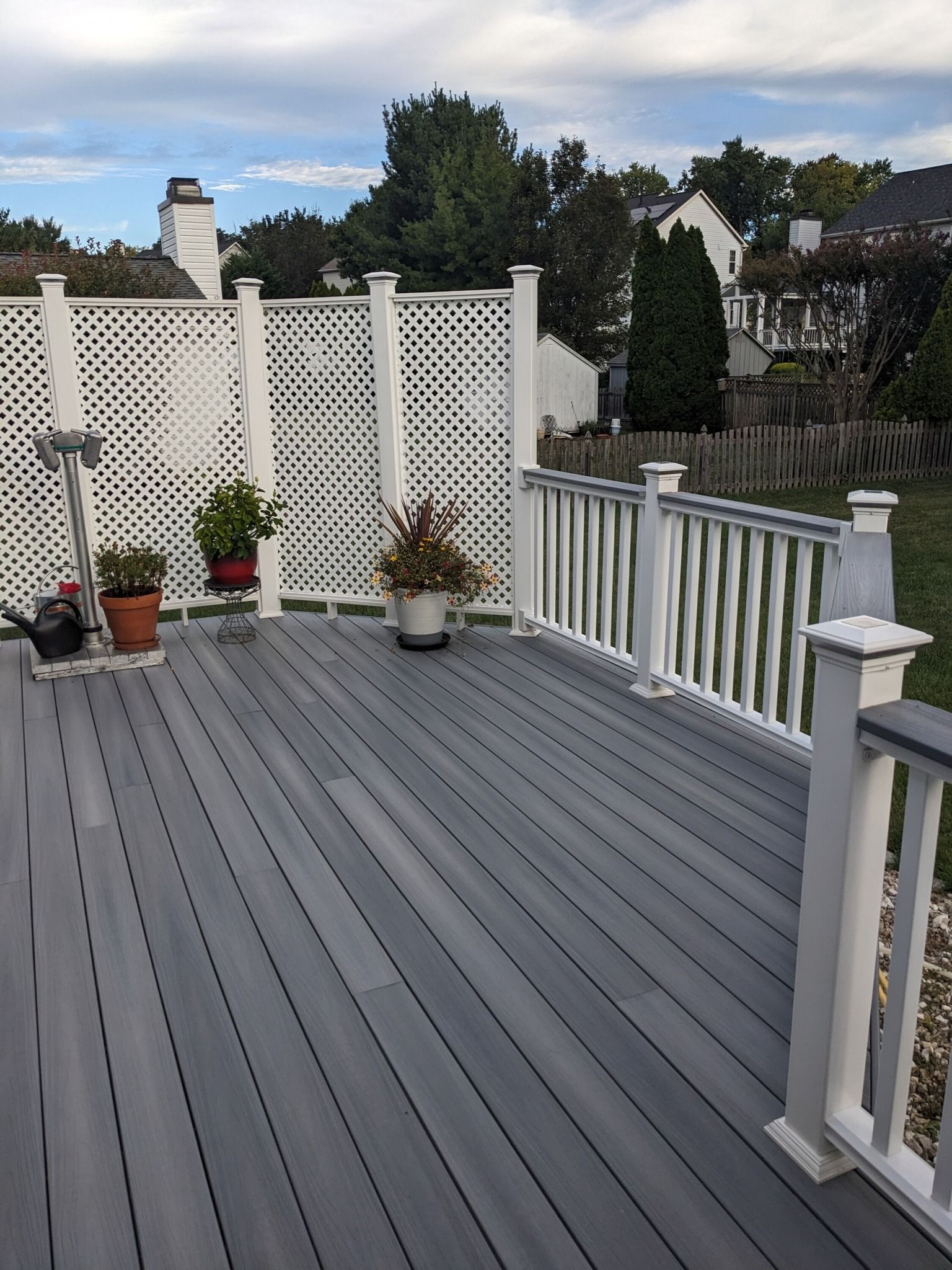 A gray deck with white railings and potted plants