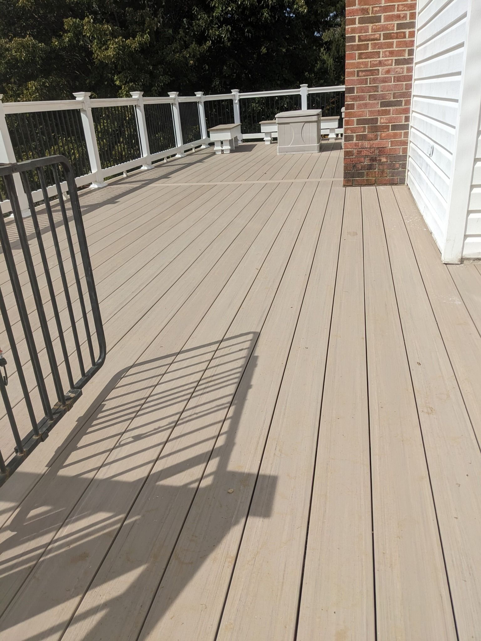 A wooden deck with a white railing and a brick chimney