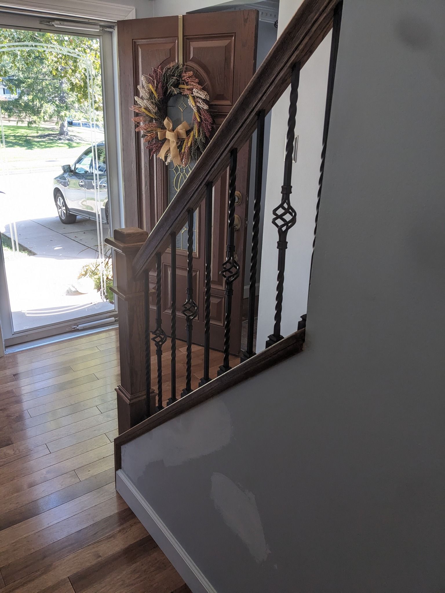 A staircase with a wreath hanging on the railing and a door in the background.