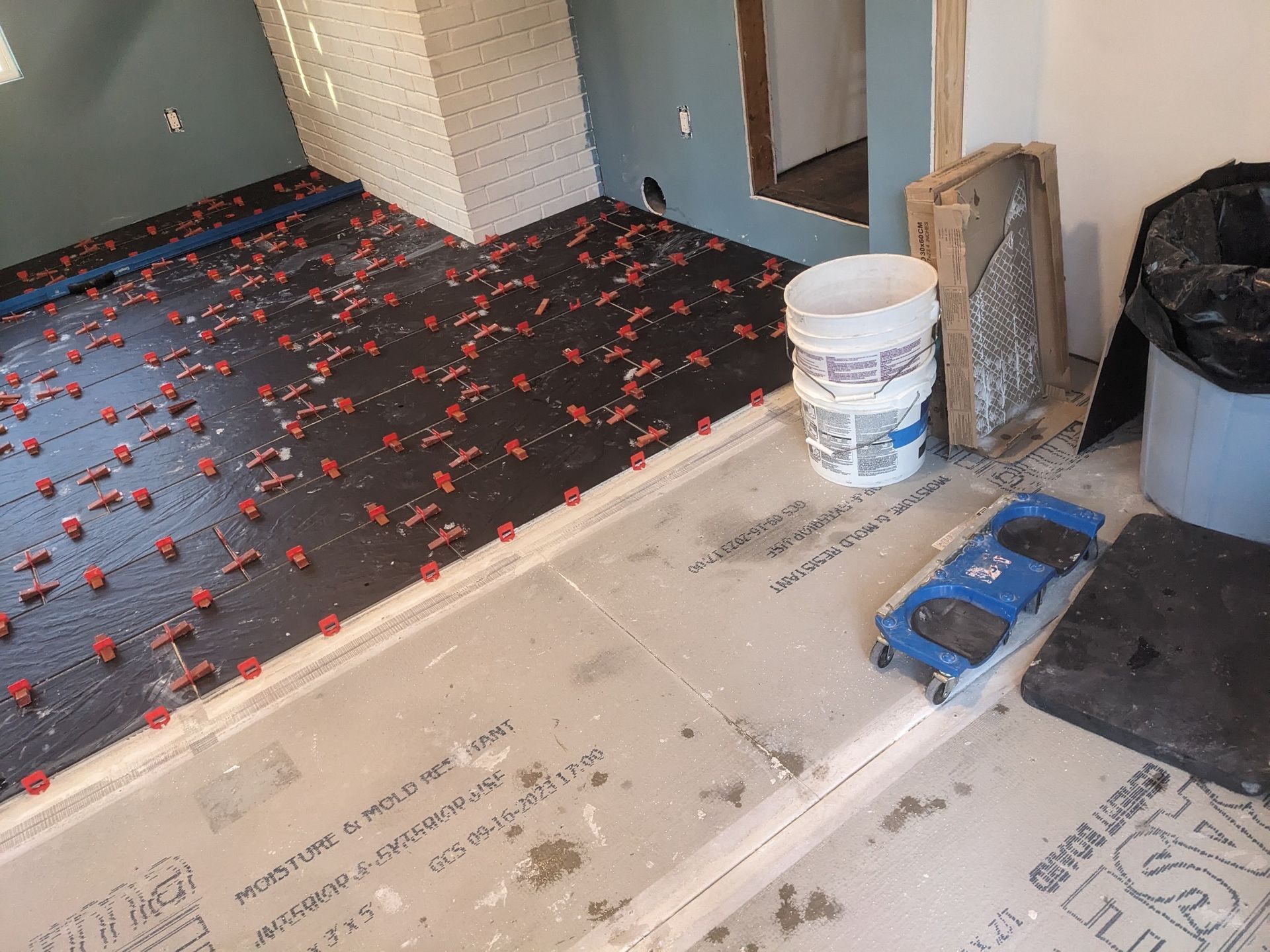 A bucket of concrete is sitting on the floor of a room under construction.