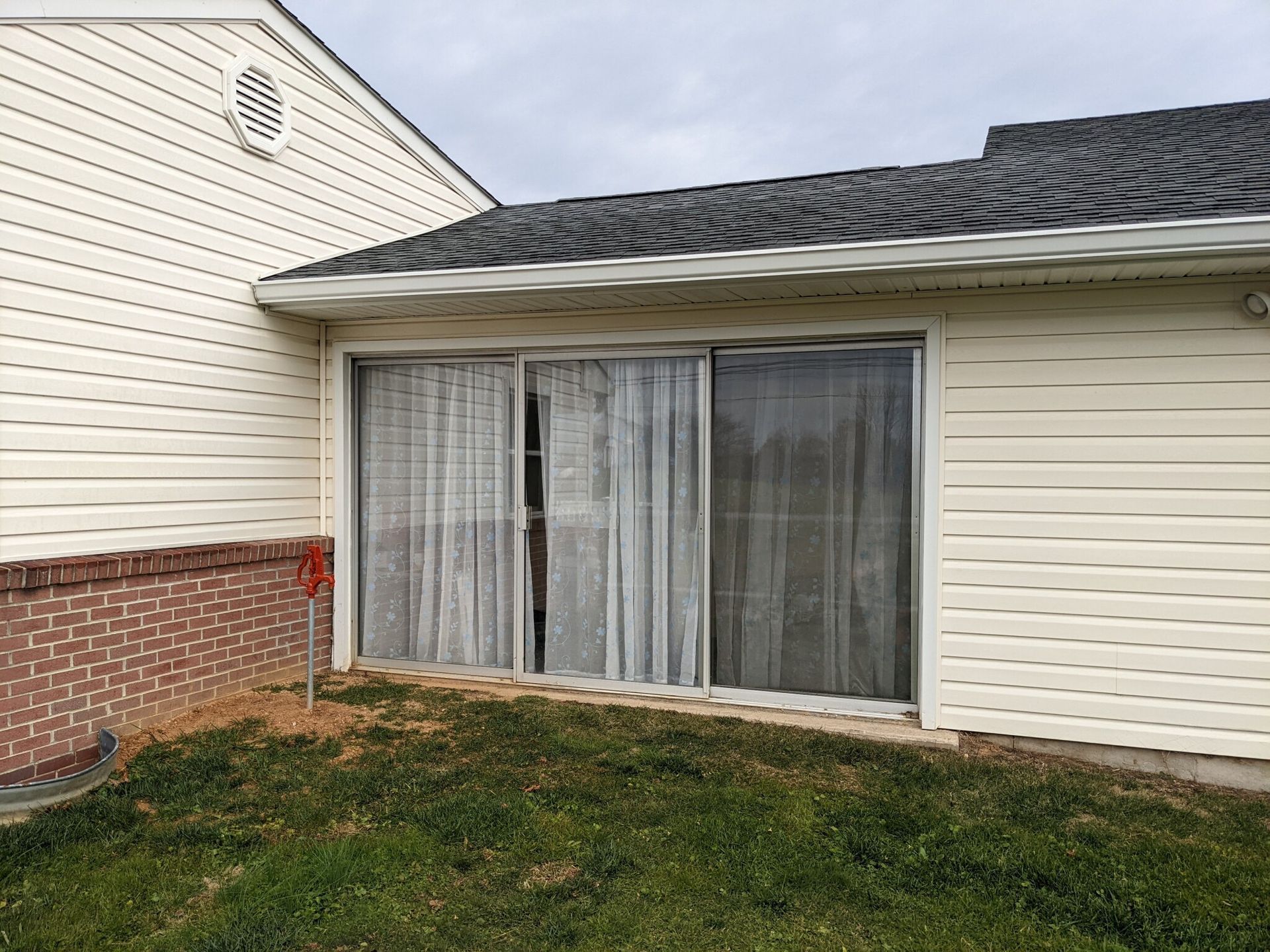 A house with a sliding glass door and curtains on it.