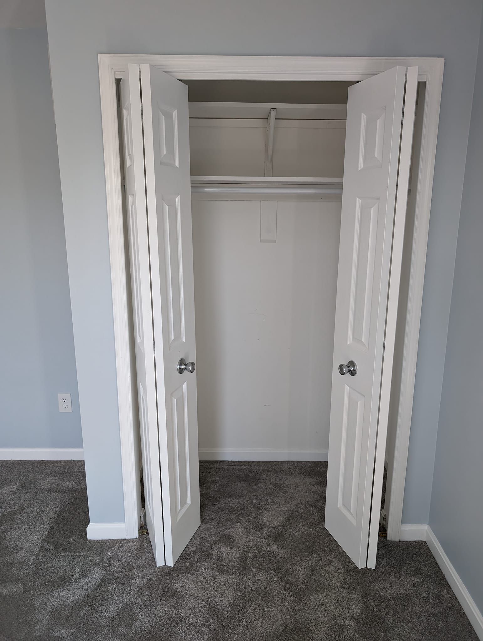 An empty closet with the doors open in a bedroom.