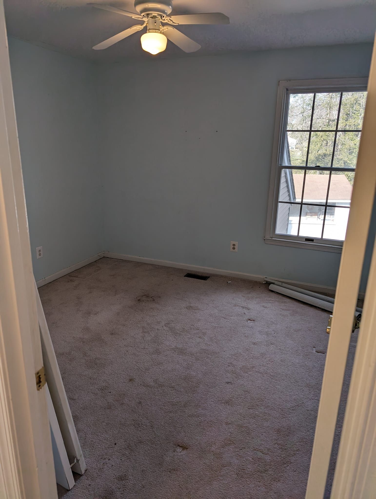 An empty bedroom with a ceiling fan and a window