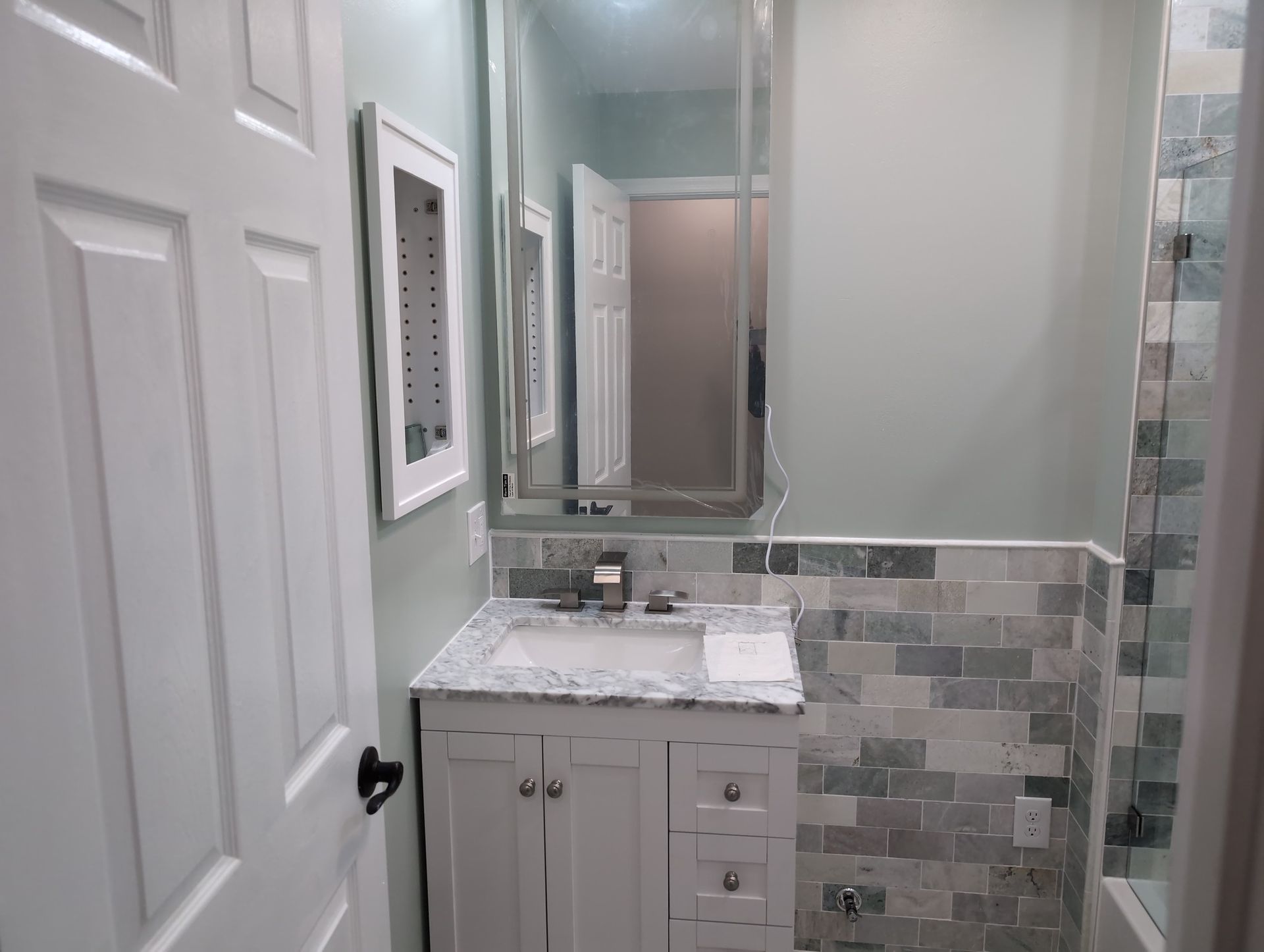A bathroom with a sink , mirror and shower.