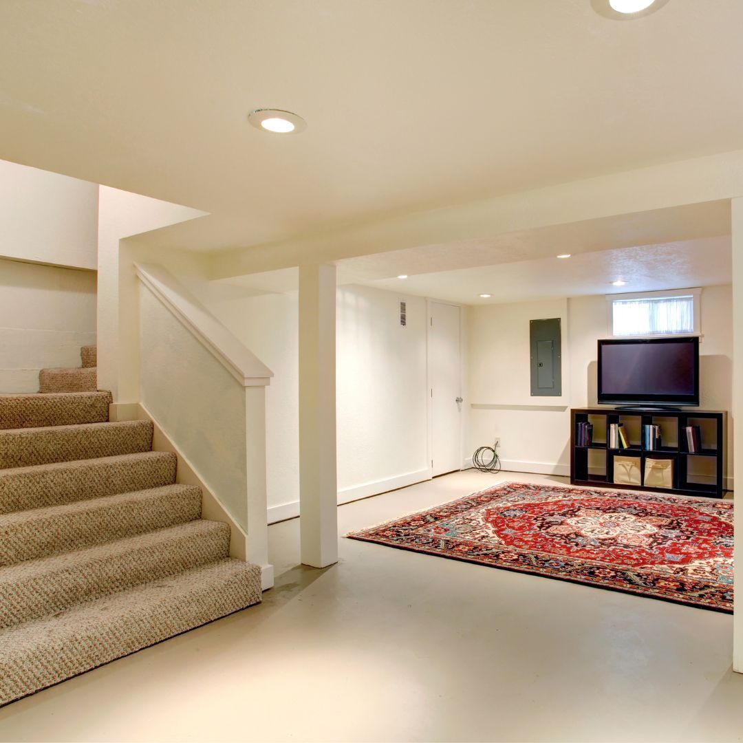 A basement with stairs and a rug and a flat screen tv