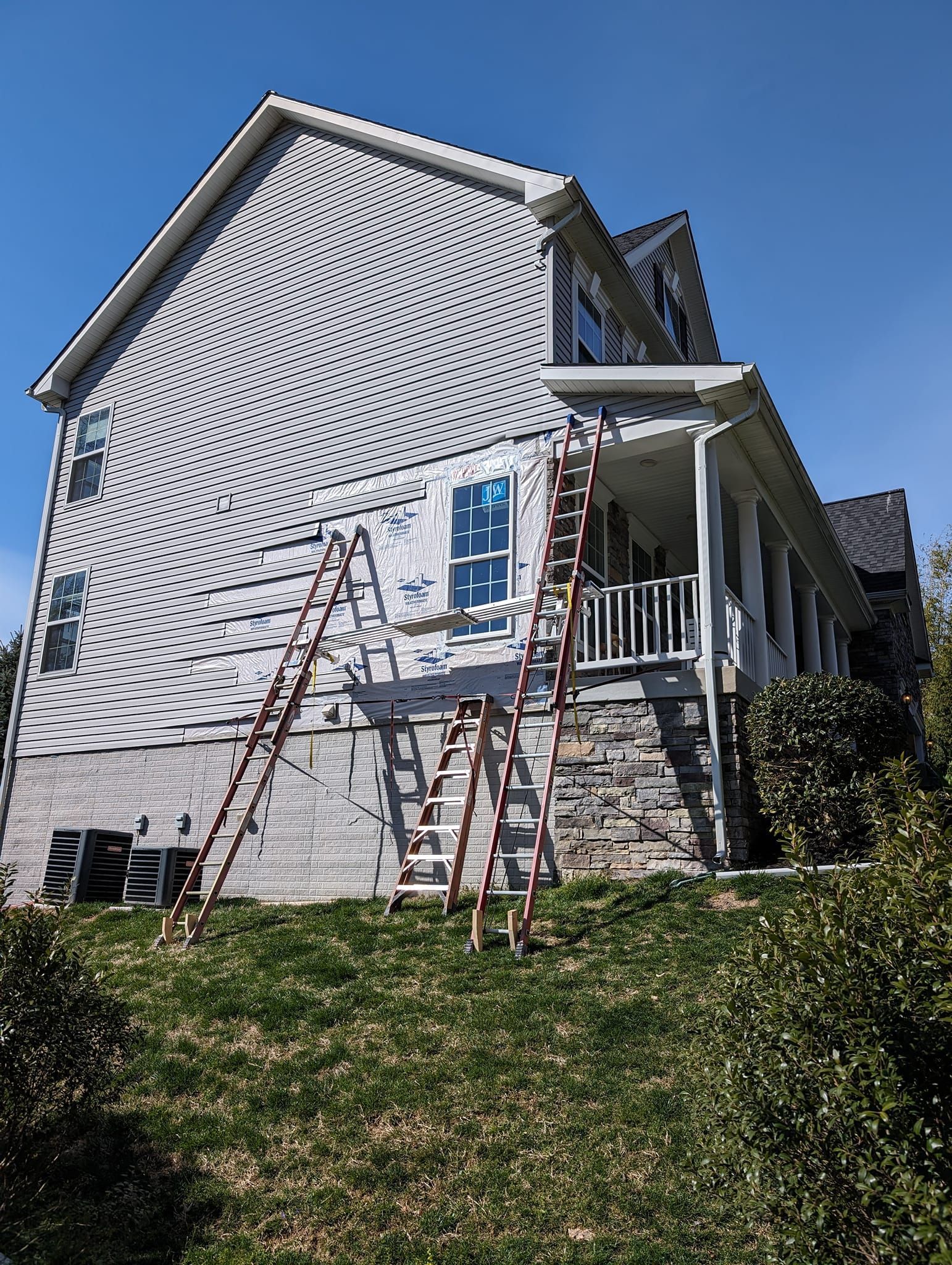 A house is being painted with a ladder on the side of it.