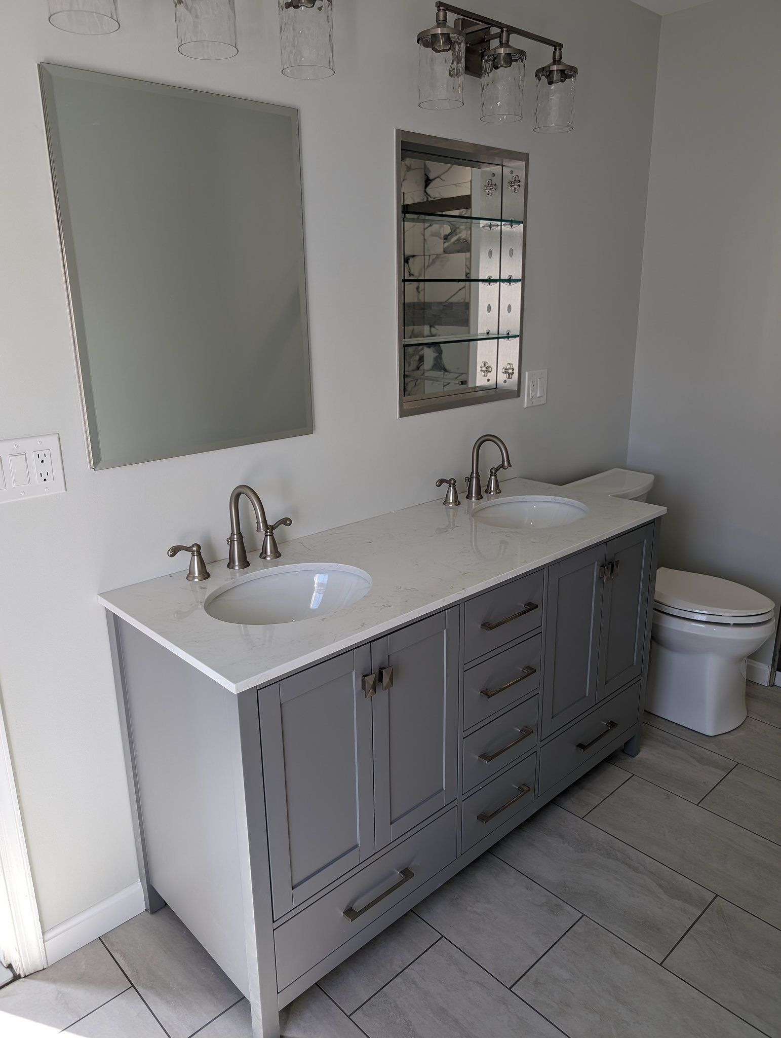 A bathroom with two sinks , a toilet and a mirror.