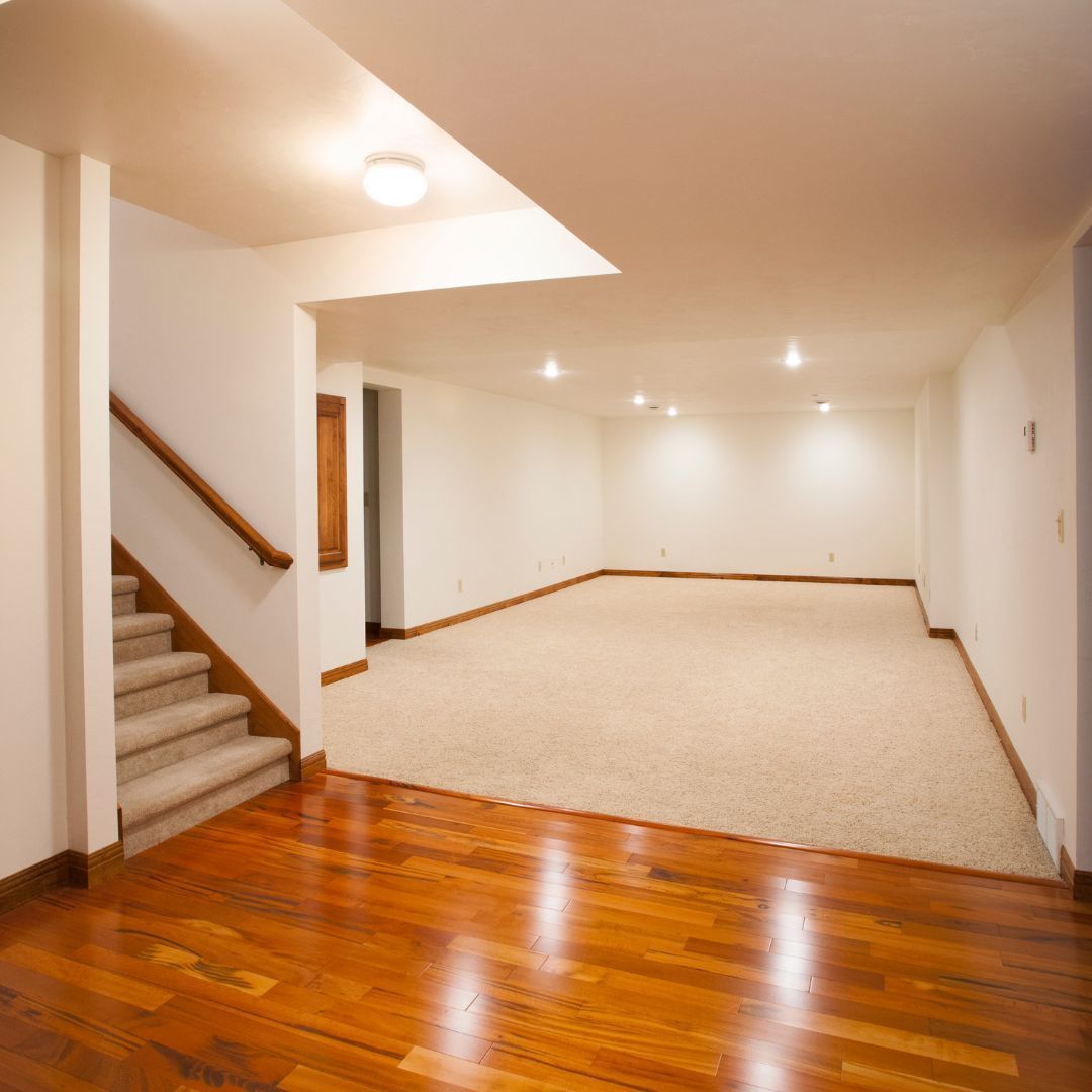 An empty basement with hardwood floors and stairs