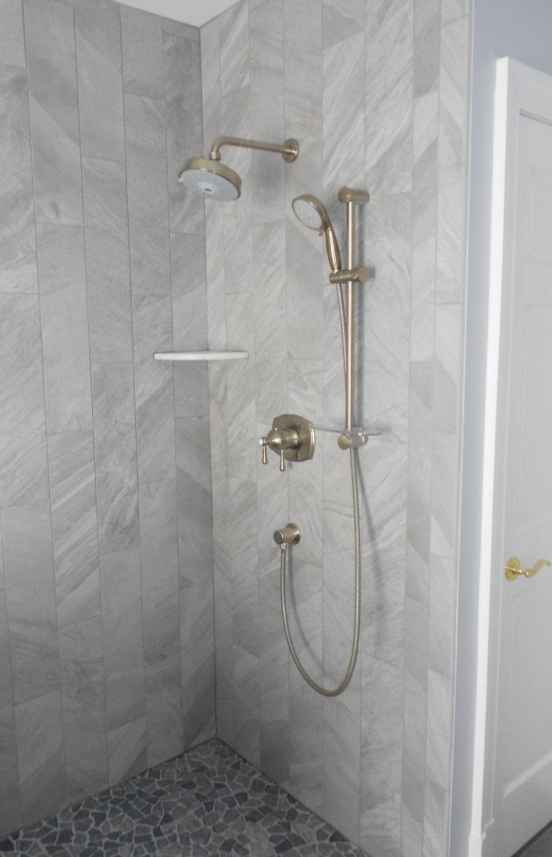 A bathroom with a walk in shower and a shower head.