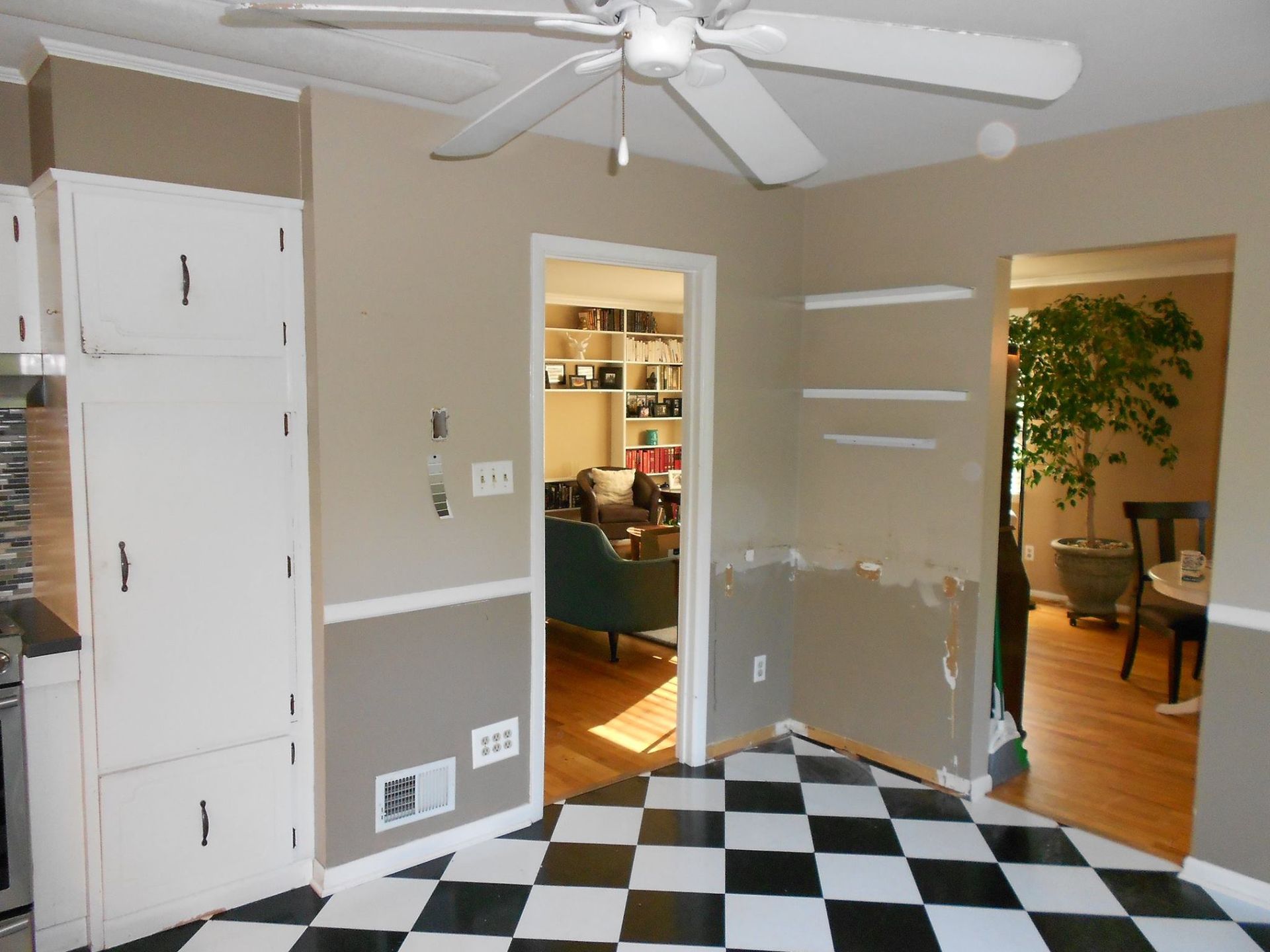 A kitchen with a checkered floor and a ceiling fan