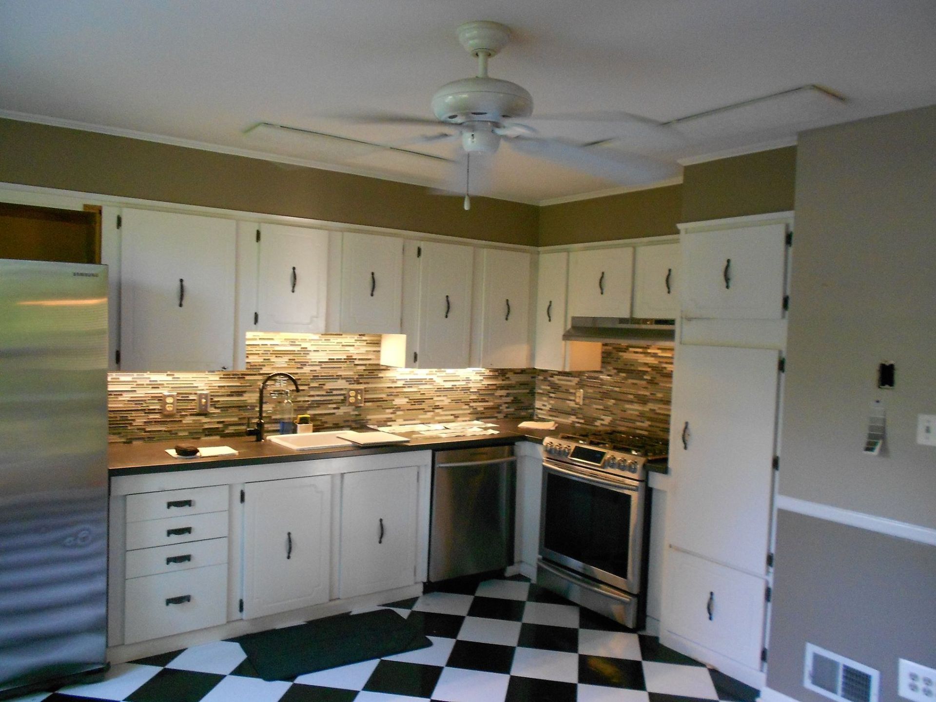 A kitchen with a checkered floor and a ceiling fan