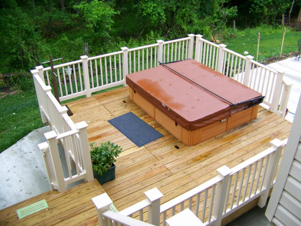 A hot tub on a deck with a white railing