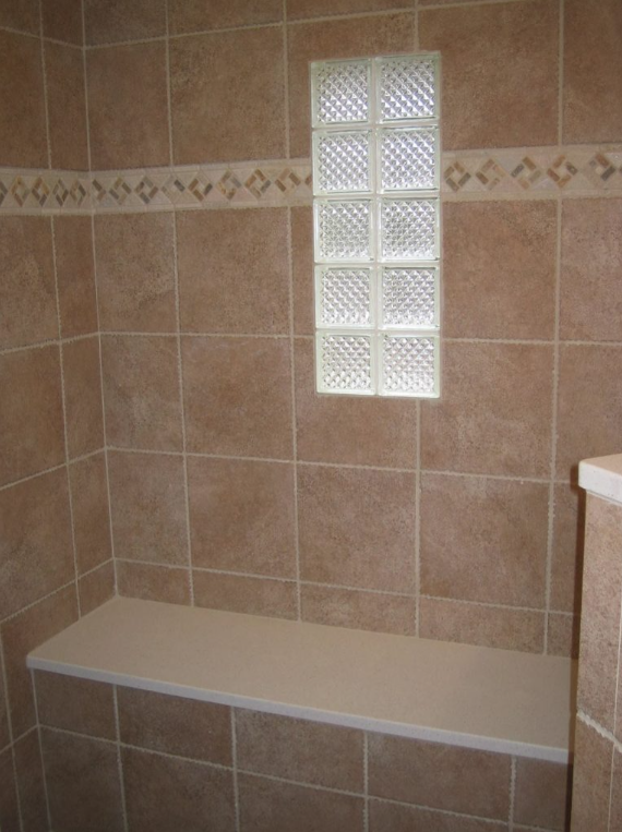 A bathroom with brown tiles and a glass block window