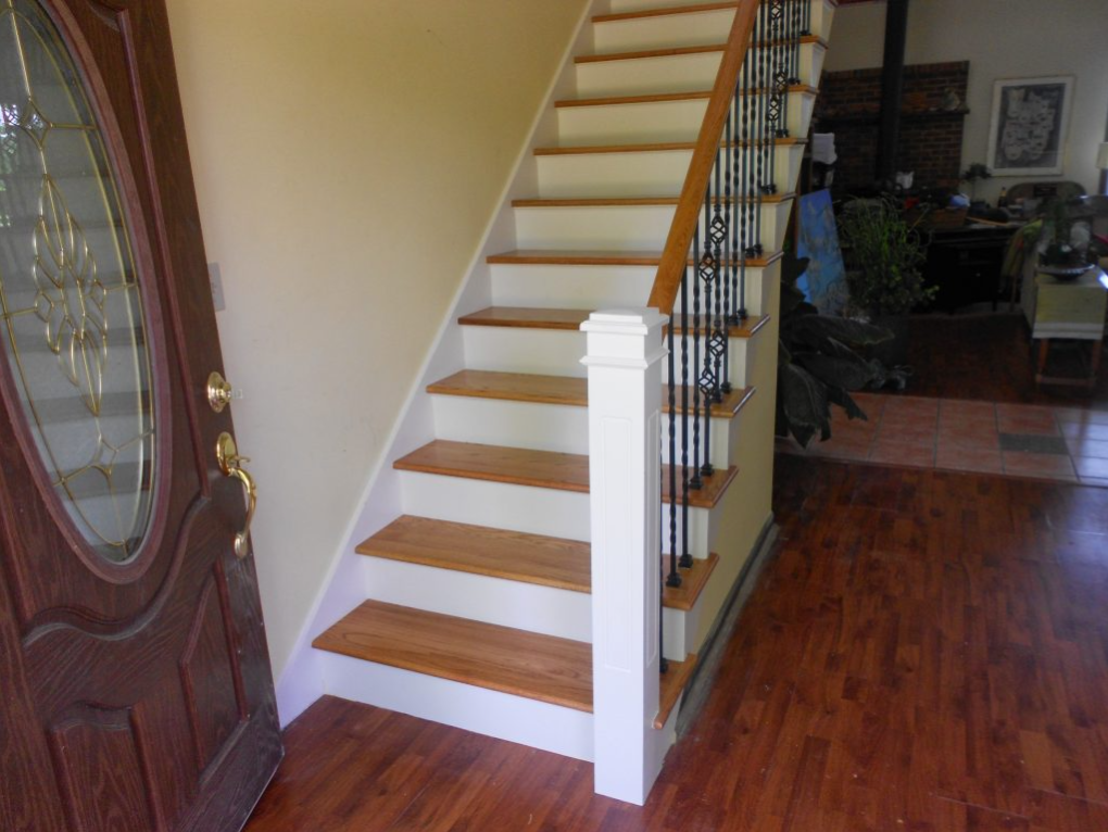 A staircase with wooden steps and a white railing in a hallway