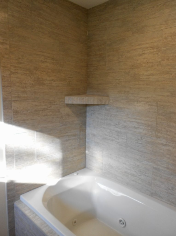 A bathroom with a bathtub and a shelf on the wall.