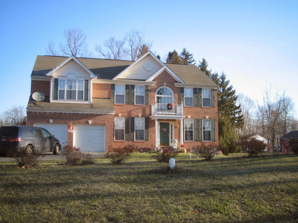 A large brick house with a car parked in front of it