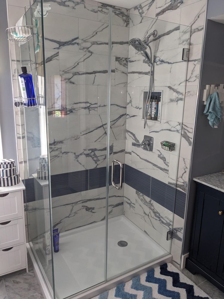 A bathroom with a walk in shower and a marble wall.
