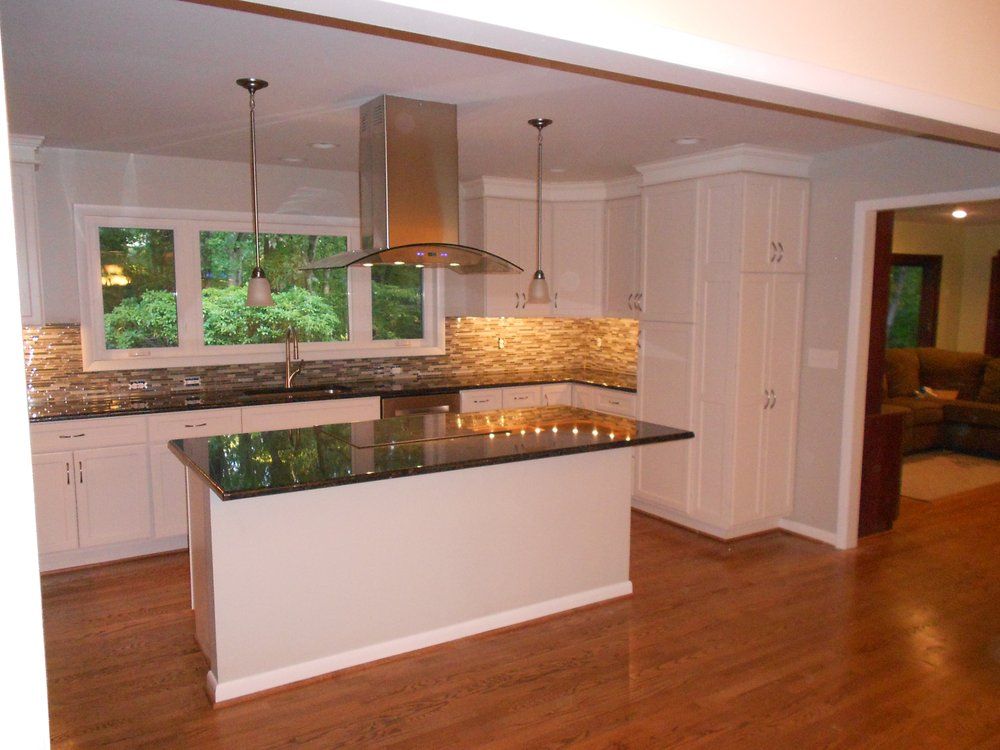 A kitchen with white cabinets and black counter tops