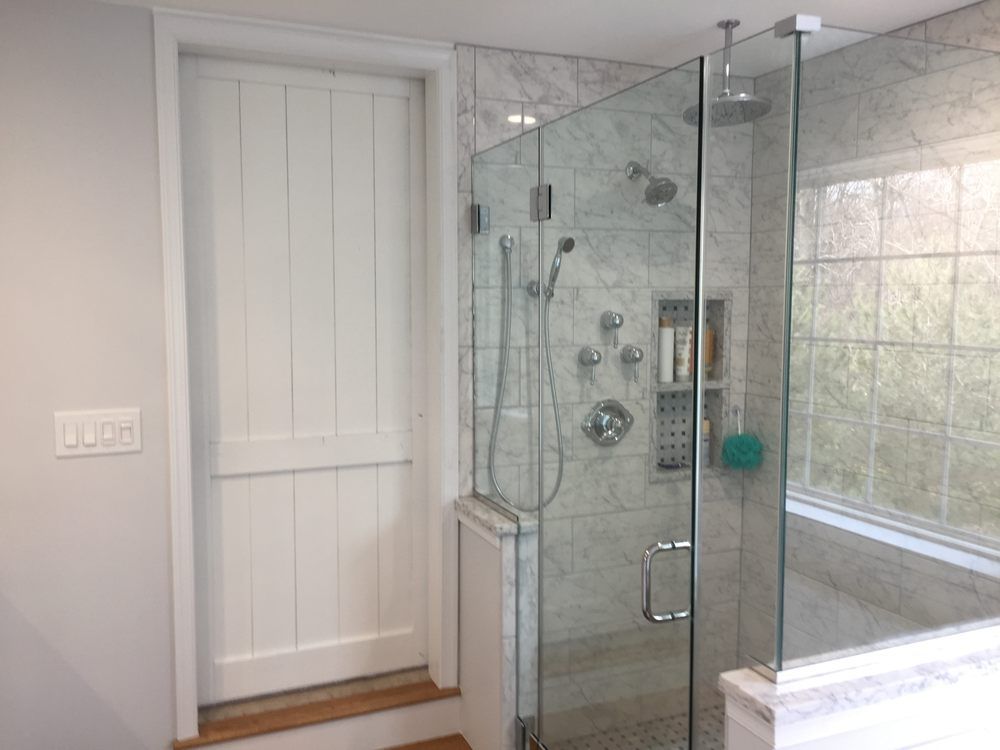 A bathroom with a walk in shower and a glass door.