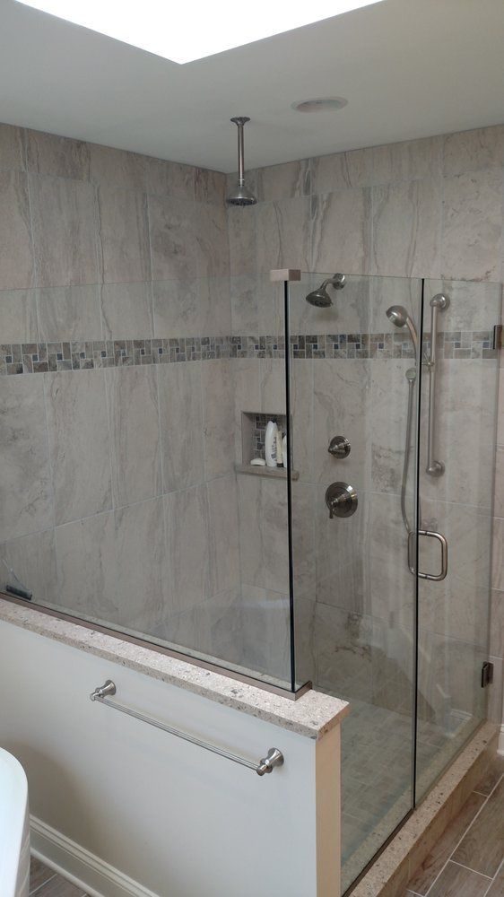 A bathroom with a walk in shower with a glass door.