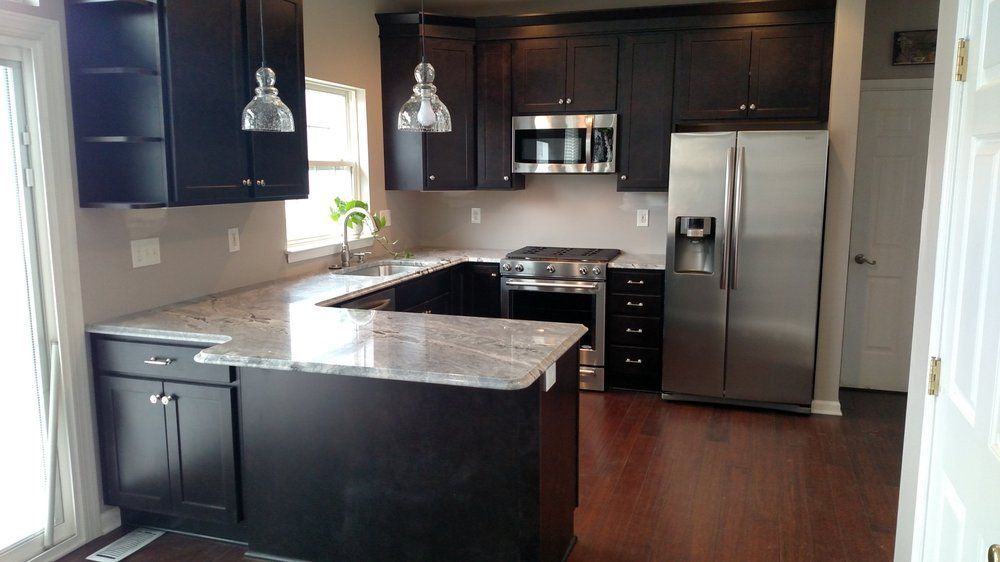 A kitchen with black cabinets and stainless steel appliances