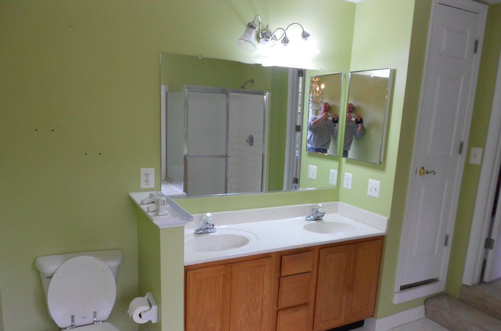 A bathroom with two sinks , a toilet , and a large mirror.