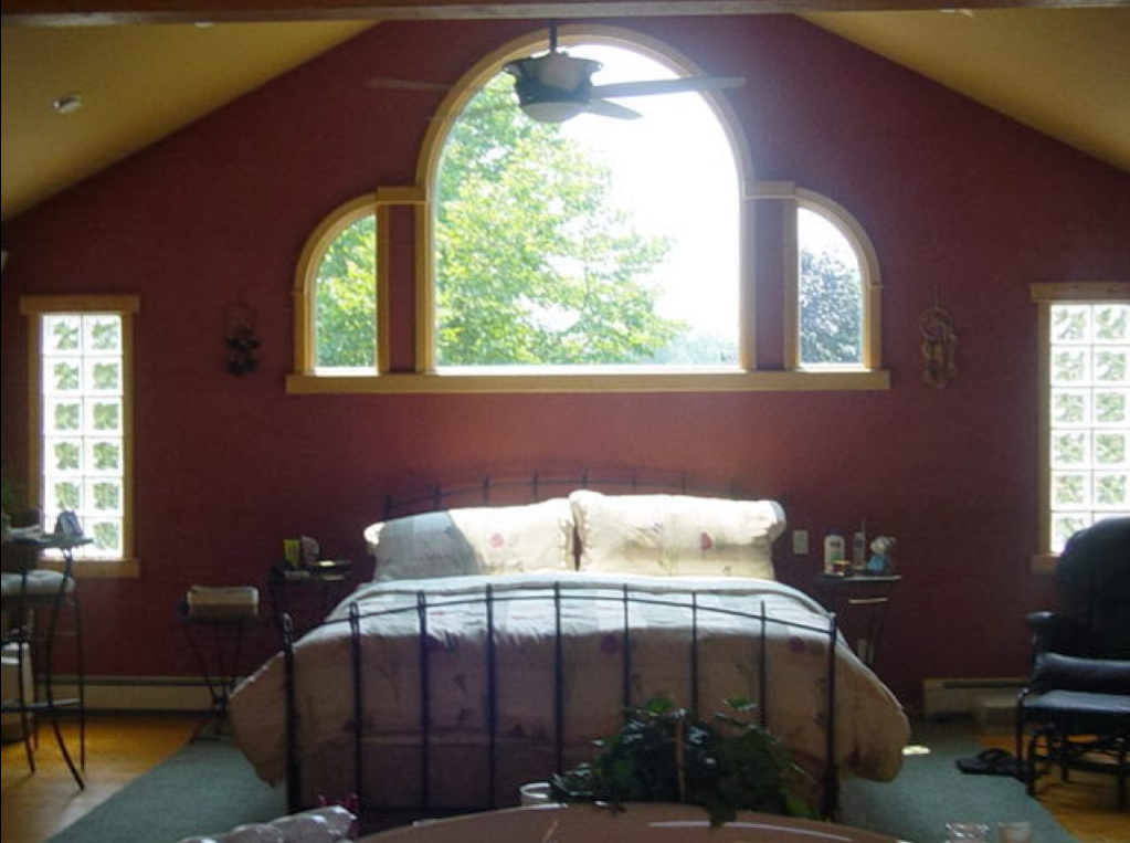 A bedroom with a large bed and a ceiling fan