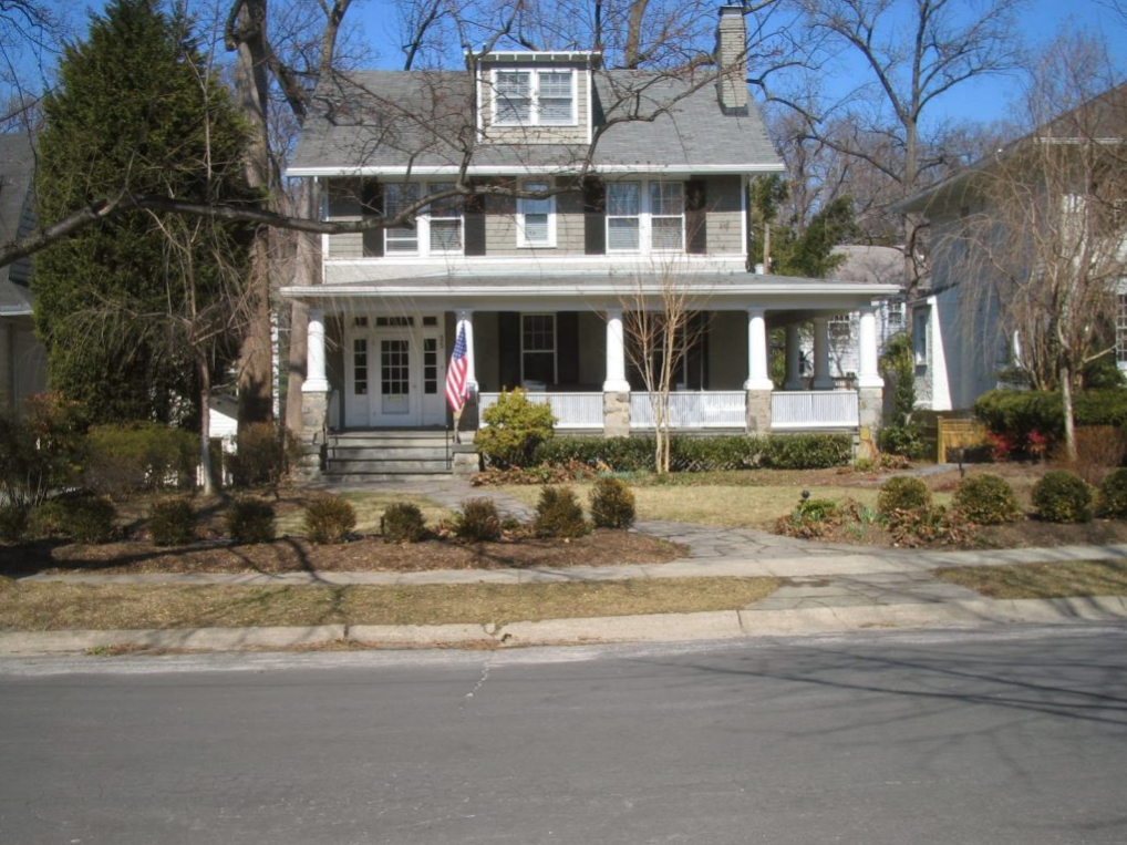 A large house with a large porch and a flag on it