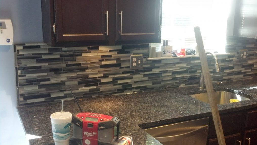 A kitchen counter with a mop and a cup of coffee on it.