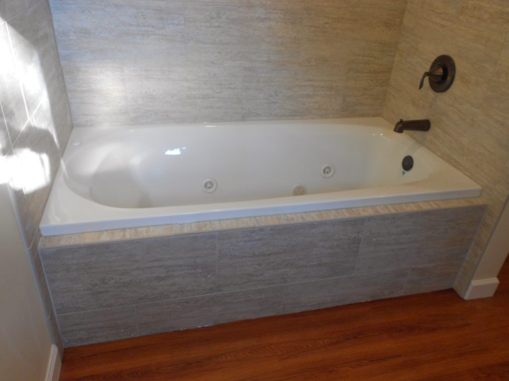 A bathtub in a bathroom with a wooden floor.