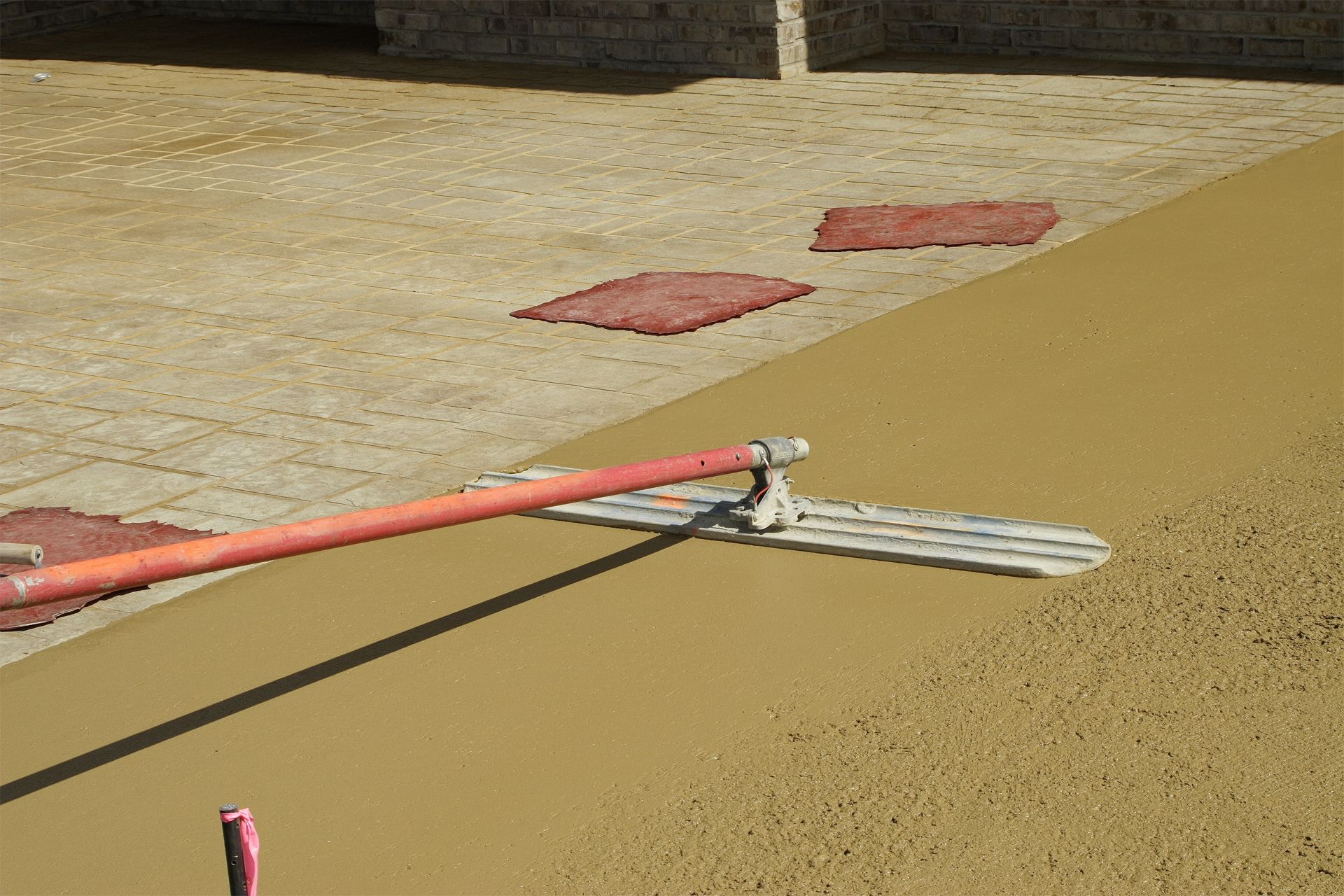 A person is using a trowel to spread concrete on the ground.