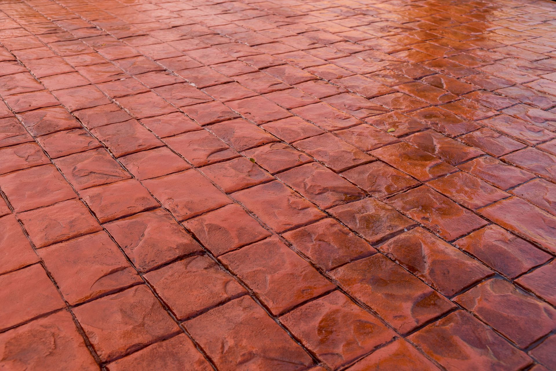A close up of a red brick floor with a diagonal pattern.