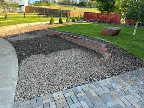 A brick walkway leading to a gravel area in a park.