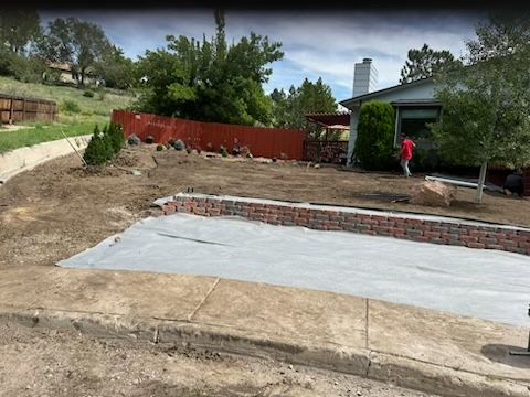 A brick wall is being built in the backyard of a house.