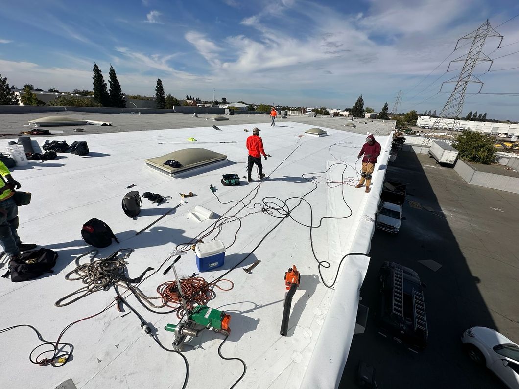 A group of men are working on a white roof