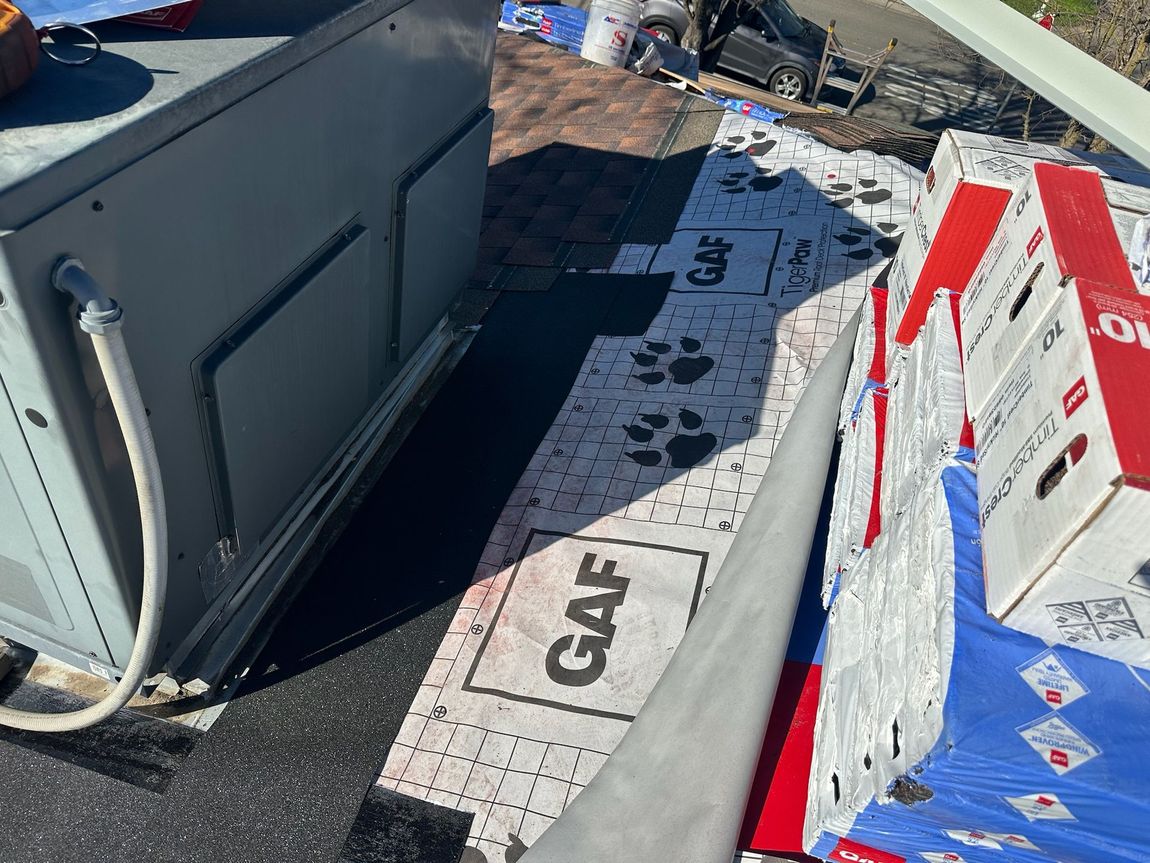 A refrigerator is sitting on top of a roof next to boxes.