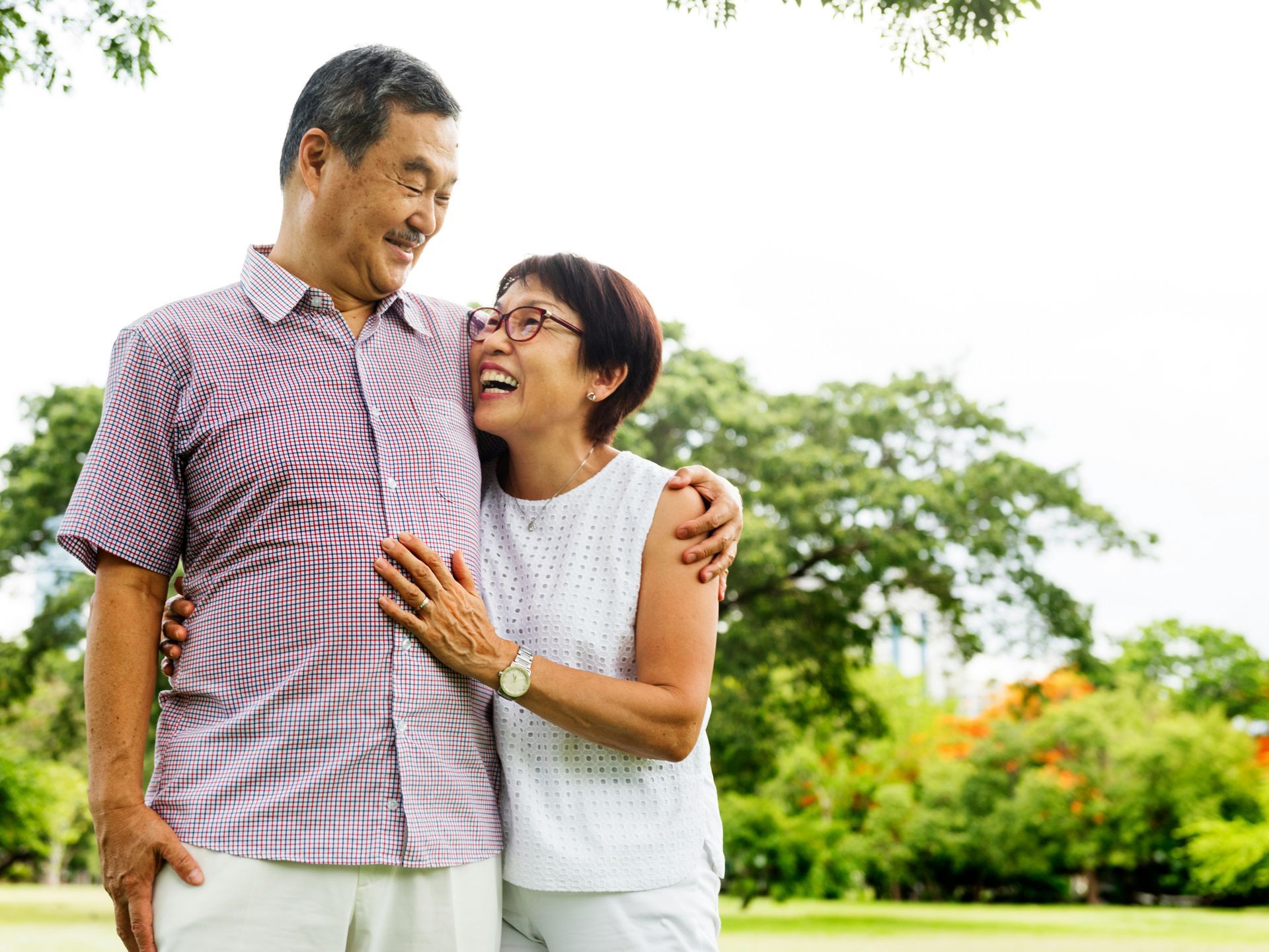 A man and a woman are standing next to each other in a park.