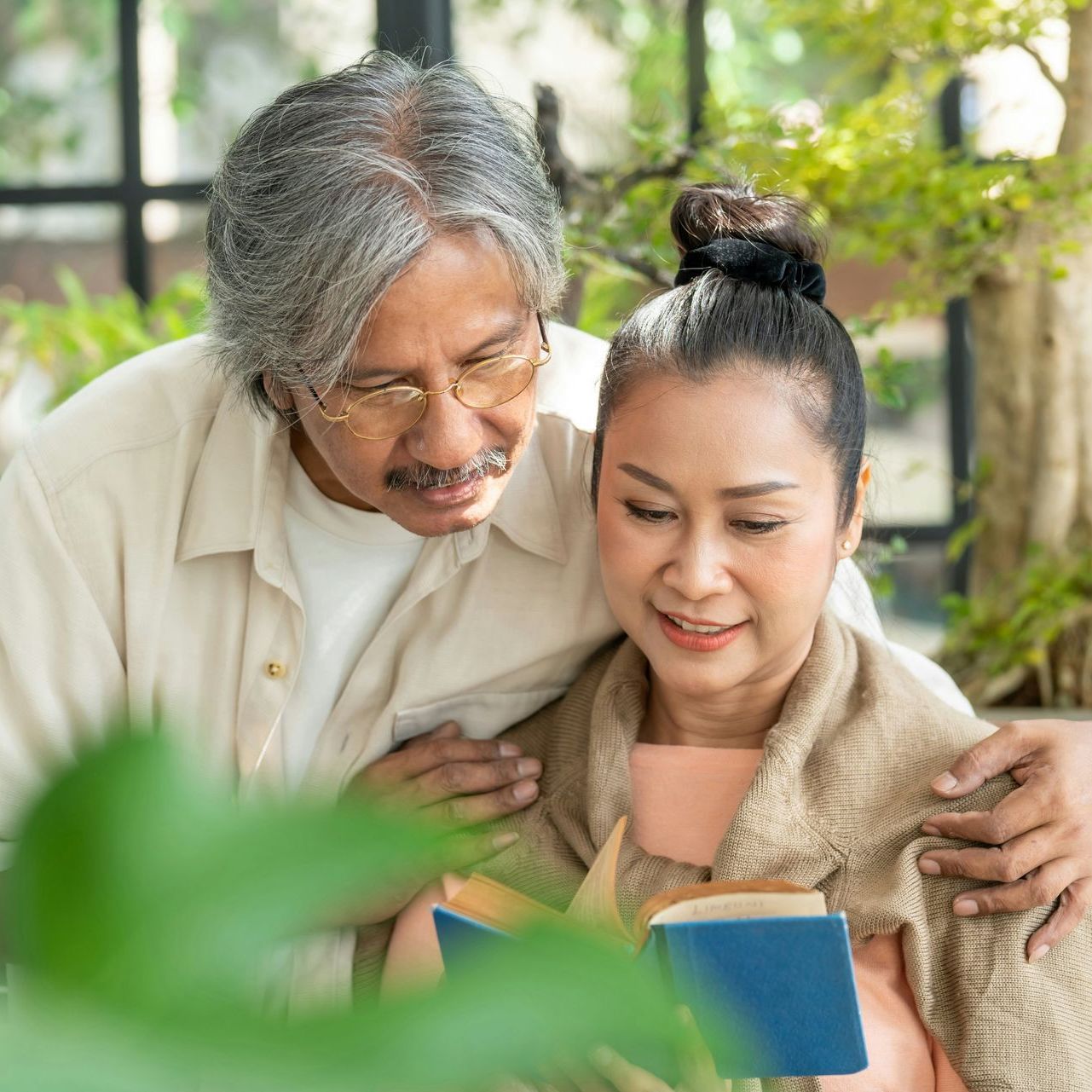 A man and a woman are reading a book together.