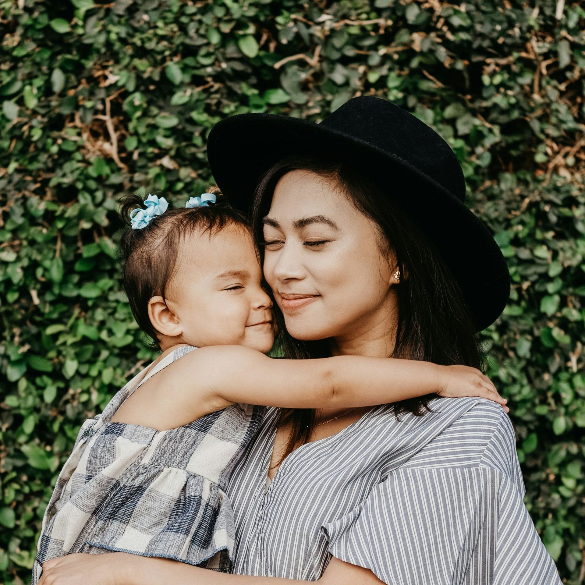 A woman in a hat is holding a little girl in her arms.