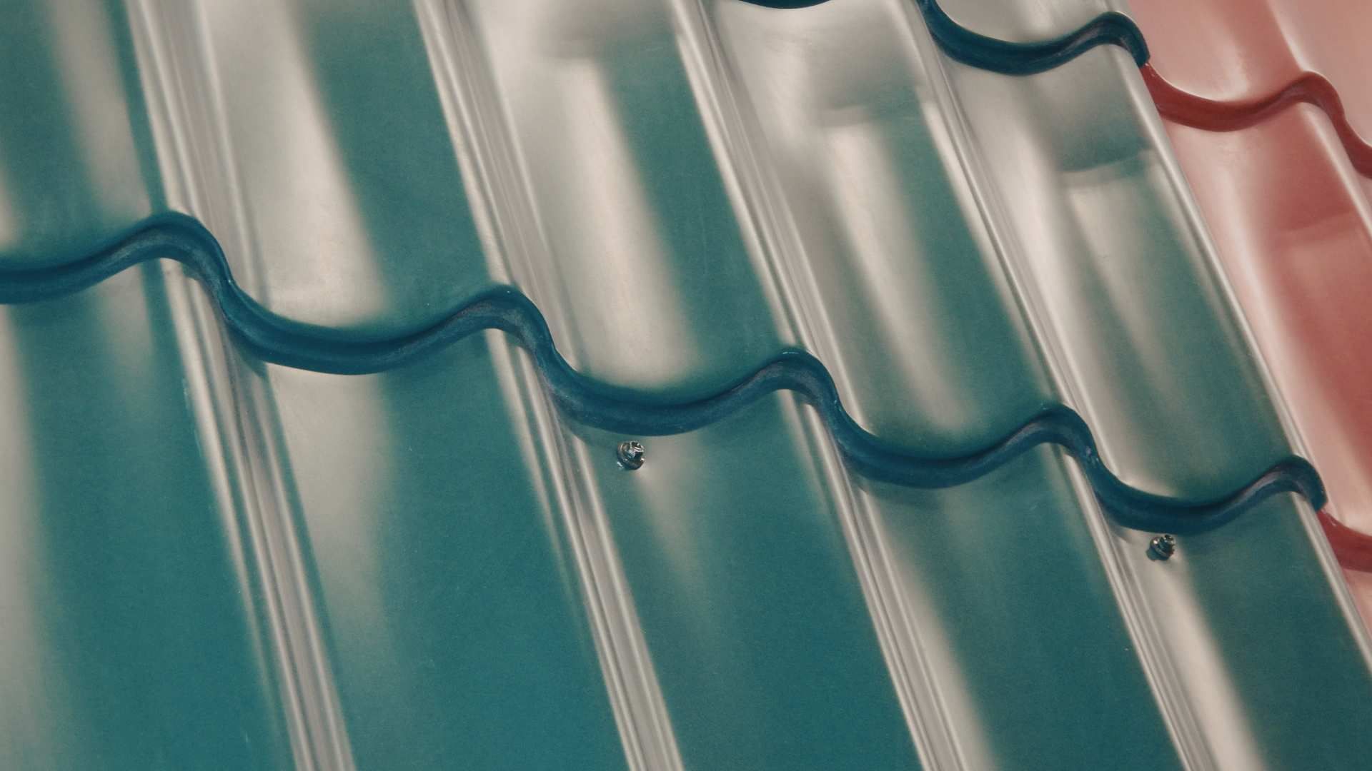 A close-up view of overlapping corrugated metal roofing panels in shades of dark green and reddish-brown.