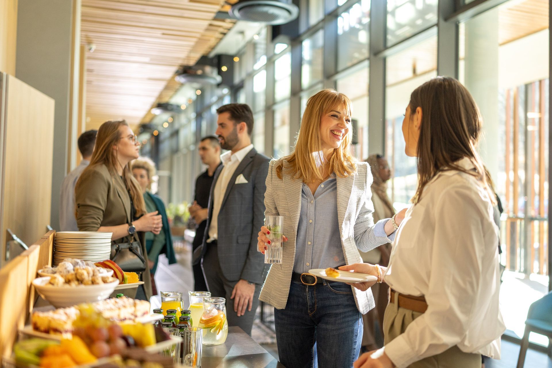 People socializing and eating at a networking event with food and drinks.