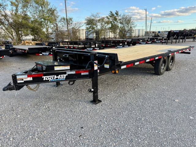 An excavator is sitting on top of a trailer on a dirt road.