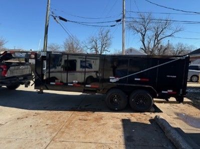 A dump trailer is parked in a parking lot next to a truck.