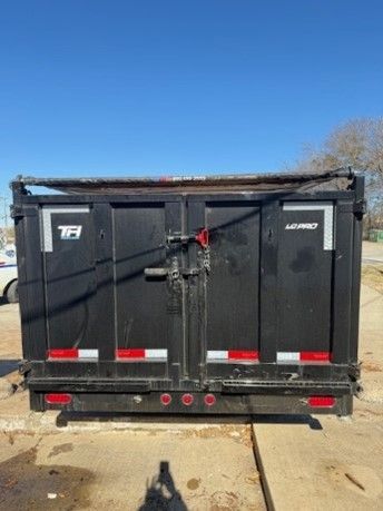 A black dumpster is parked on the side of the road.