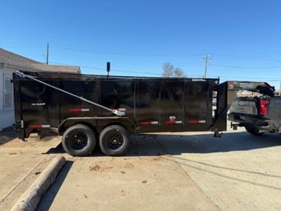 A dumpster trailer is parked next to a truck in a parking lot.