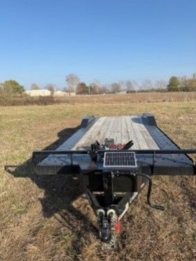 A trailer with a solar panel attached to it is parked in a field.