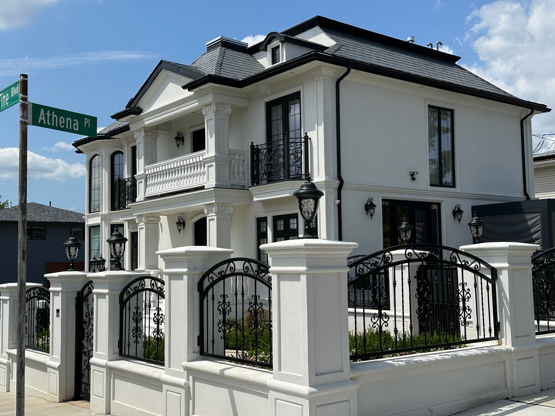 White mansion with black iron fence and street sign 